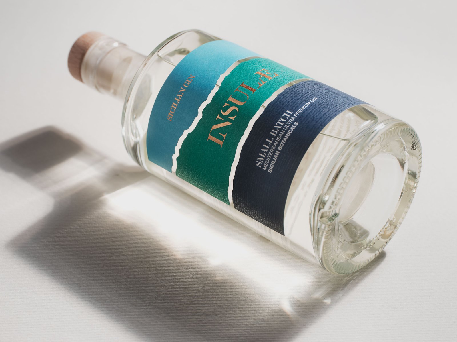 Bottiglia di Insula Sicilian Gin su fondo bianco, con l'ombra netta del vetro