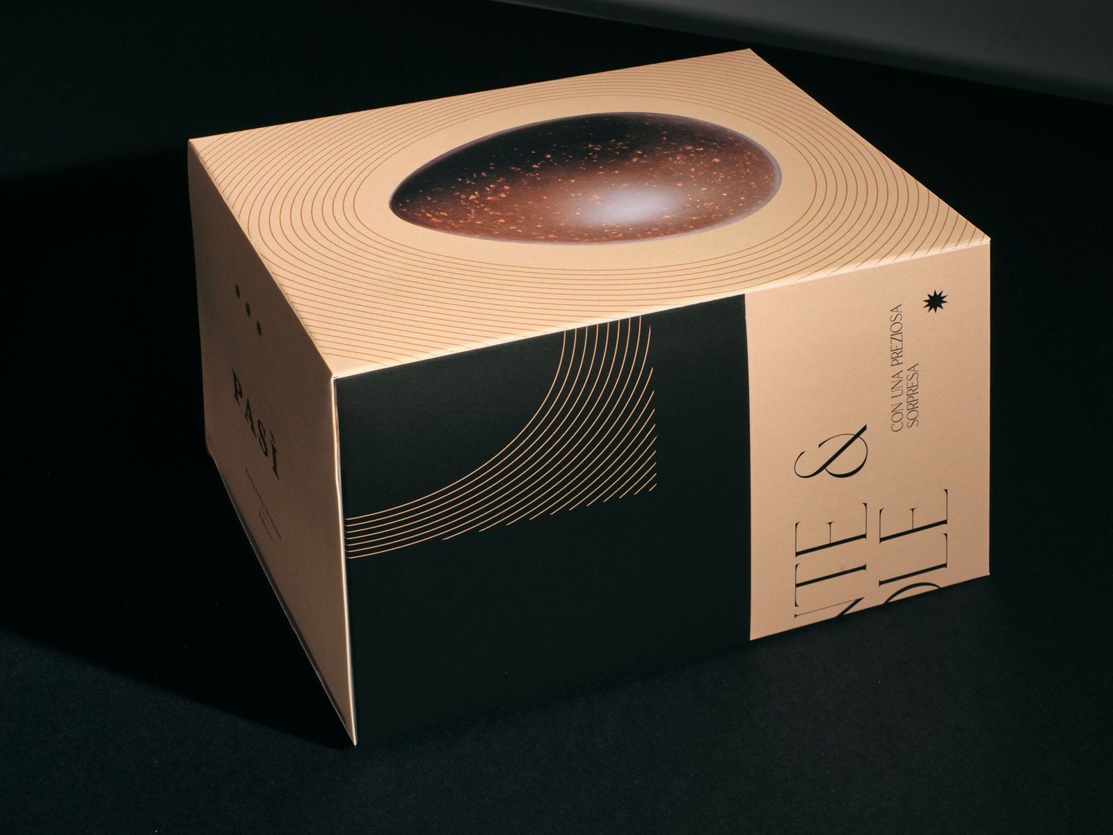 Pasì Fondente & Nocciole Easter egg box, powder pink with a black band, at three-quarters on a black set, with the egg on the lid