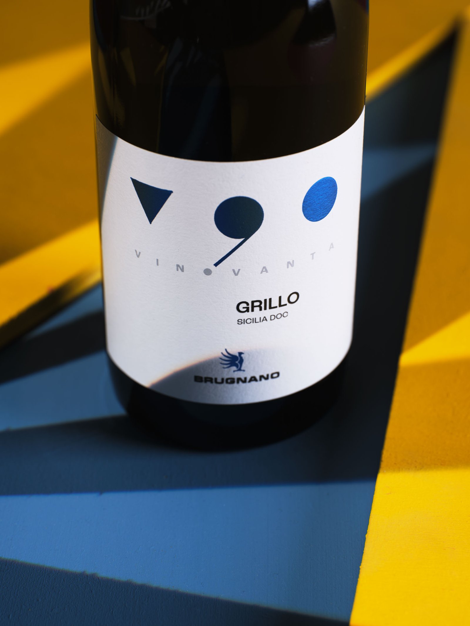 Vinovanta Grillo Sicilia DOC against blocks of yellow and blue, with a hard shadow