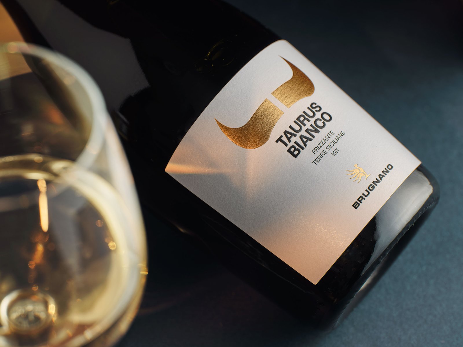 Taurus Bianco lying on a deep blue ground, the gold of the label and a glass