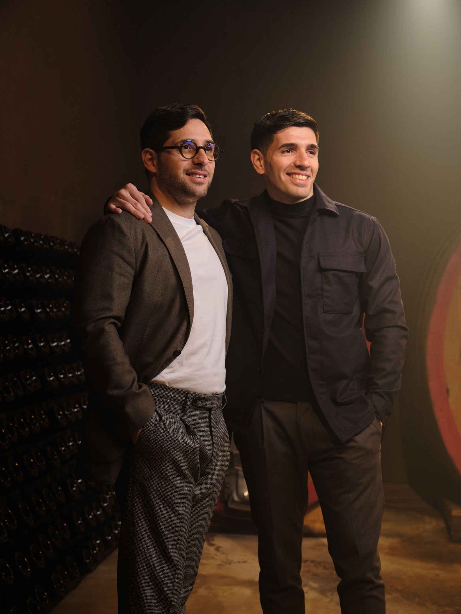 Portrait of the two owners in the cellar, beside the bottles
