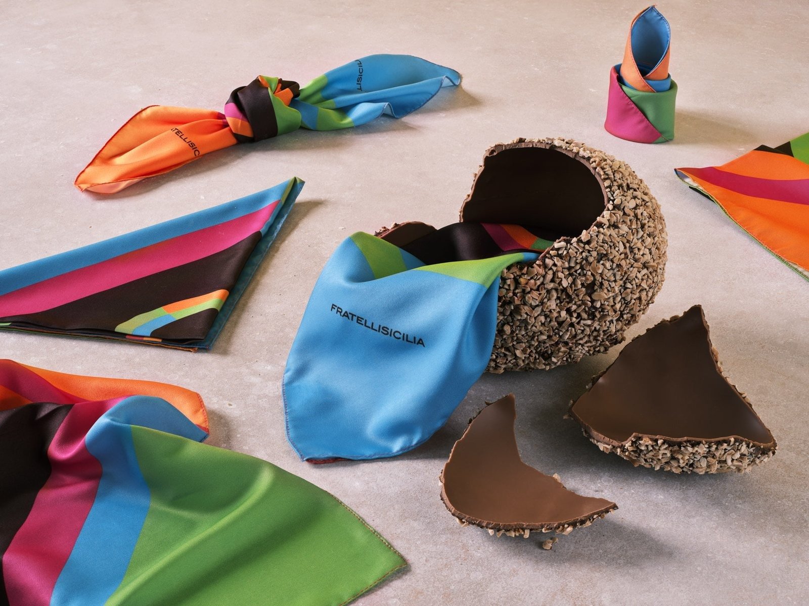 Uovo di cioccolato aperto fra foulard di seta colorati