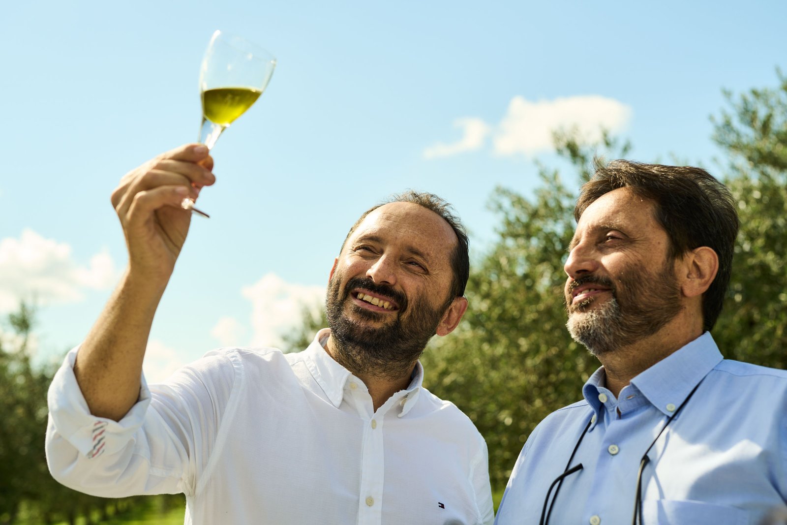 A glass of new oil held up against the sky