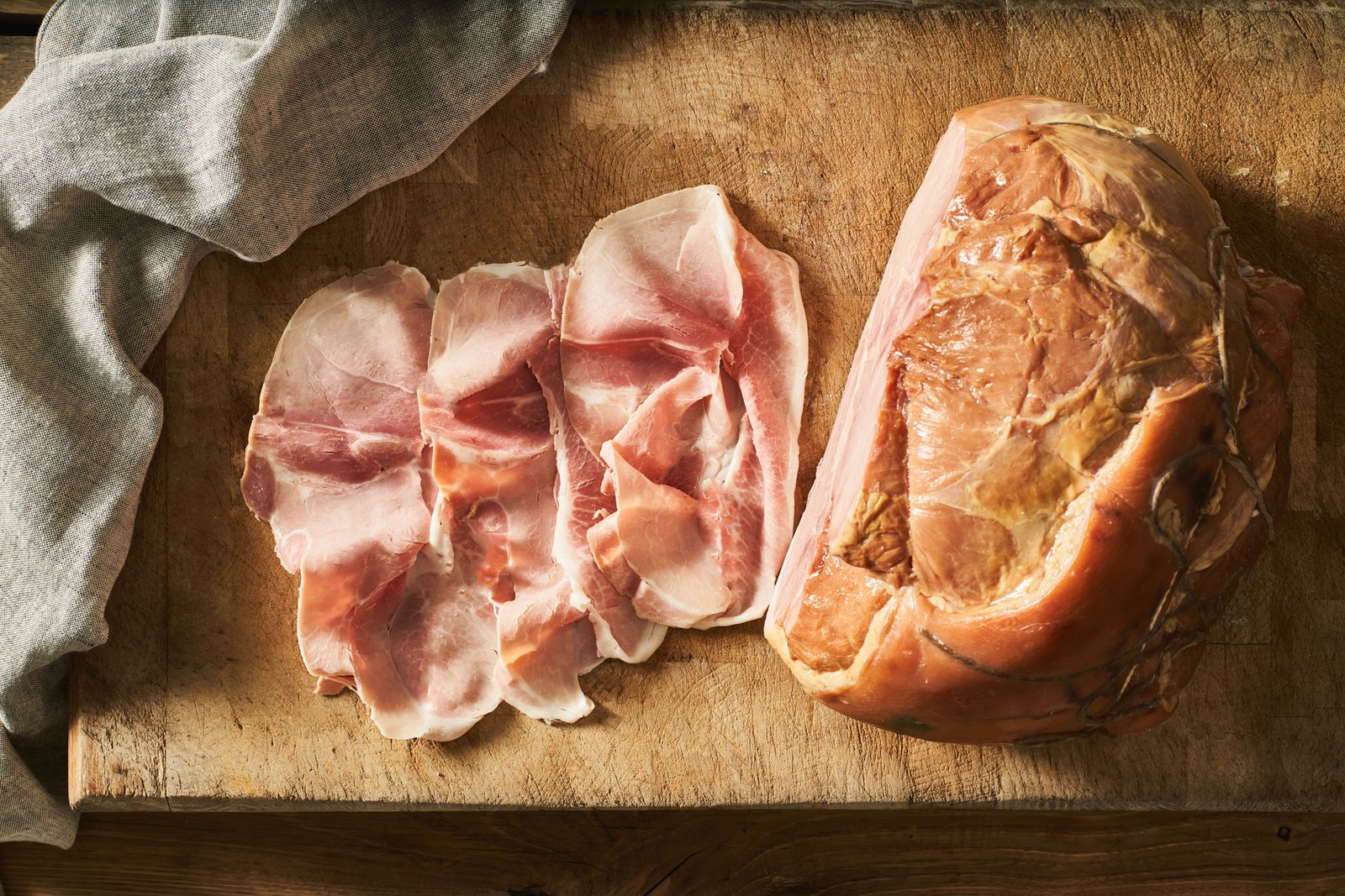 Fette di porchetta e il pezzo intero con la cotenna dorata, legato con lo spago