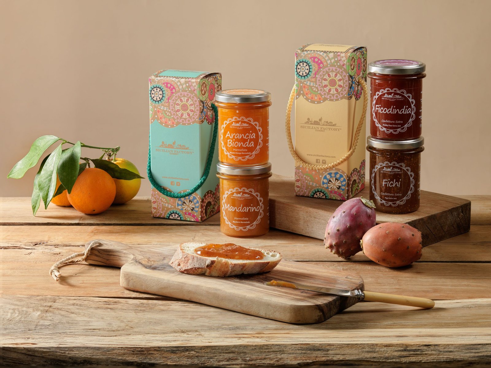 Blonde orange and mandarin marmalades, prickly pear and fig jams and two gift boxes on a wooden table, with a slice of bread spread with marmalade, oranges and prickly pears