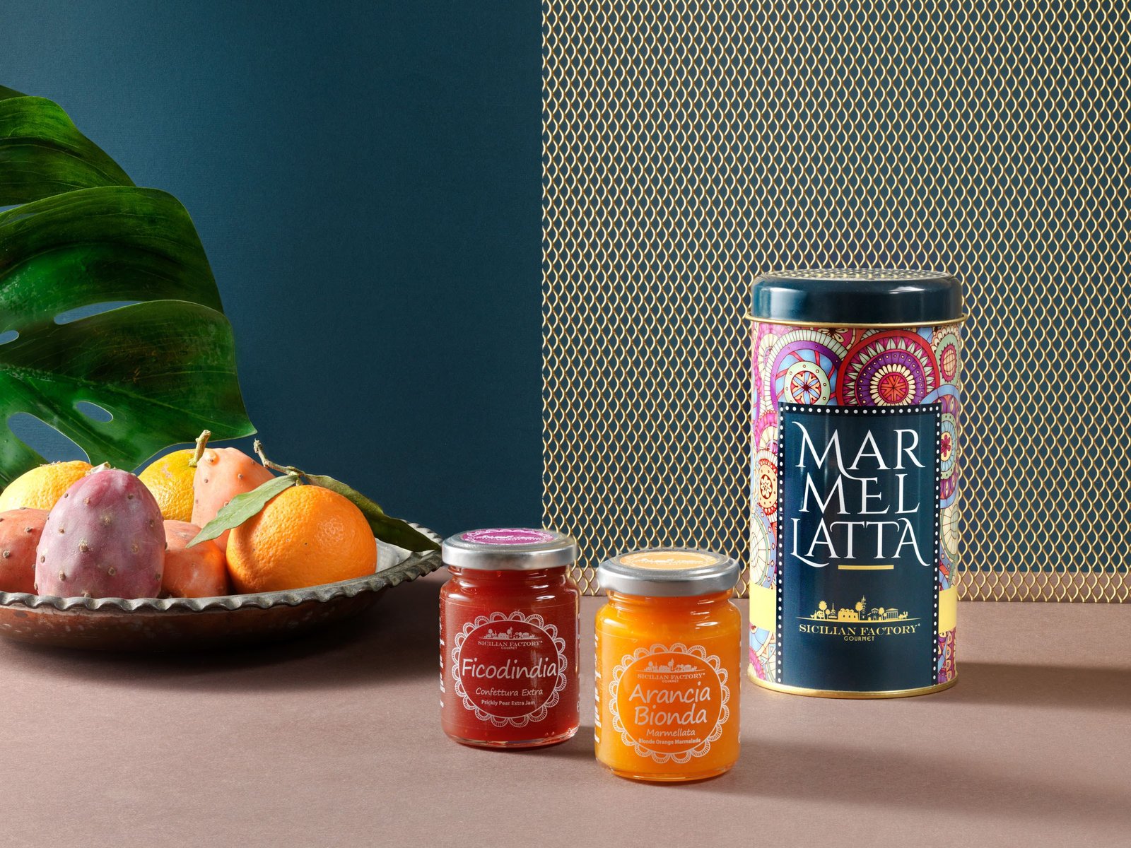 Prickly pear jam, blonde orange marmalade and the «Marmellatta» tin, with a dish of prickly pears and oranges and a monstera leaf