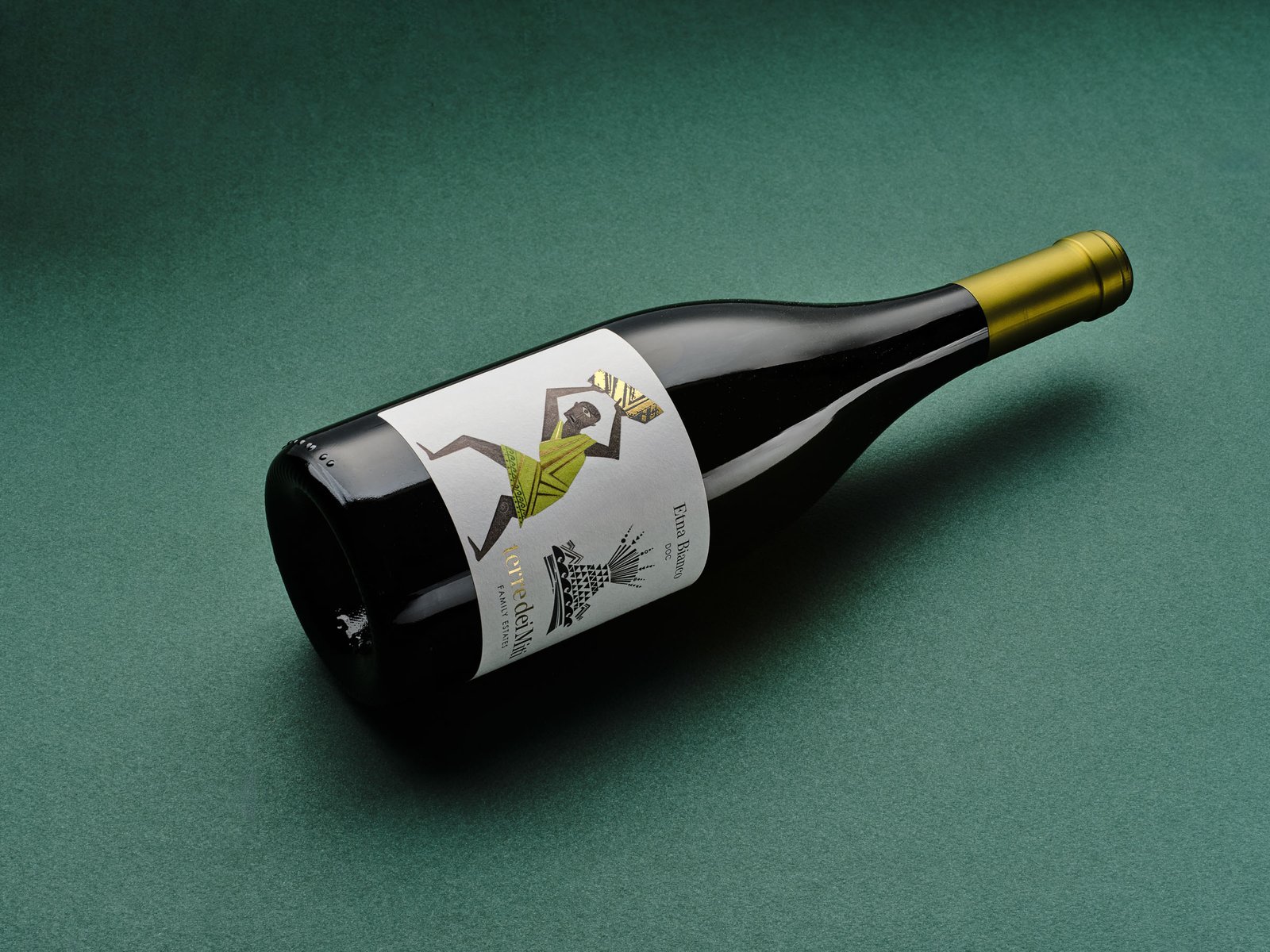 Terre dei Miti Etna Bianco lying on green paper, with its gold capsule and the Polyphemus label