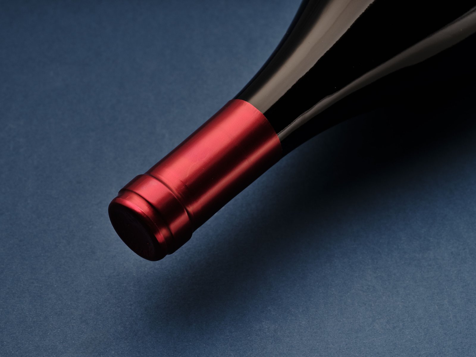 Red capsule of the Terre dei Miti Etna Rosso on blue paper