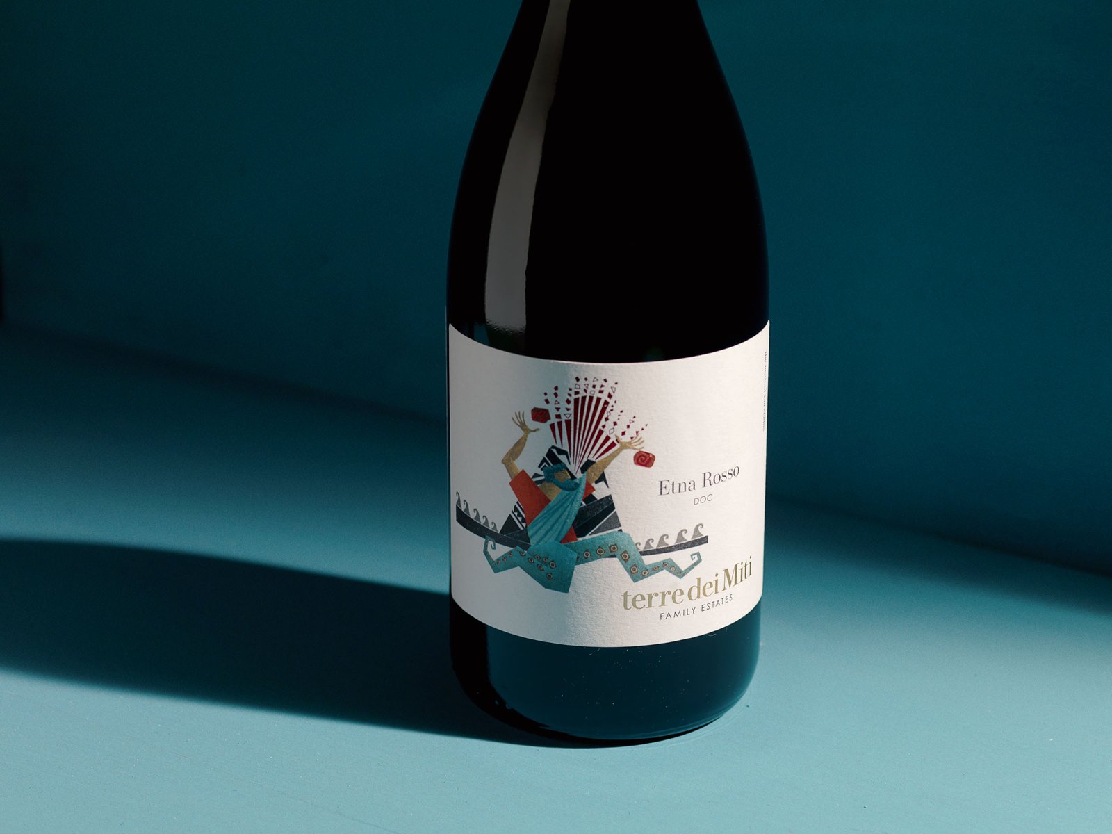 Terre dei Miti Etna Rosso label with the figure of Enceladus and the red shards, in the hard light of the teal set