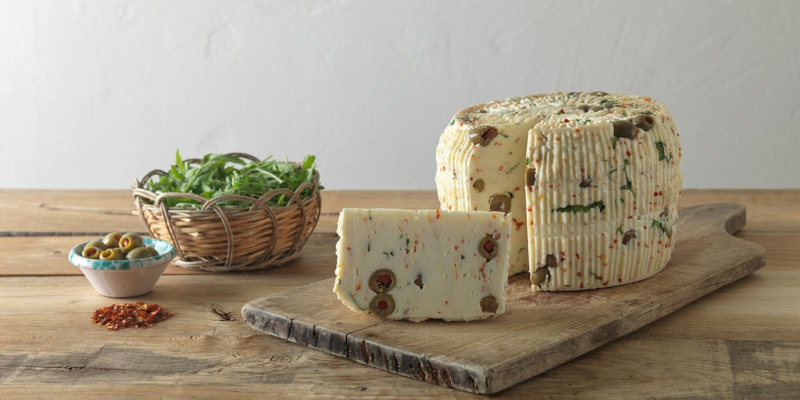 Primo sale con olive, peperoncino e rucola: lo spicchio tagliato mostra le olive verdi, accanto la rucola, le olive e il peperoncino